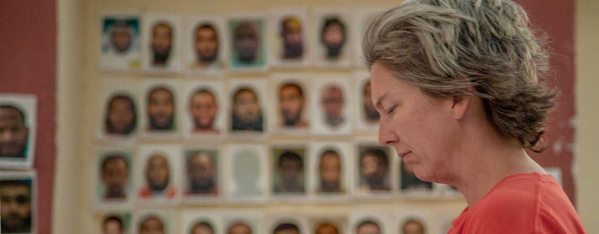Frida Berrigan Standing by a Wall of Guantánamo Detainee Photos